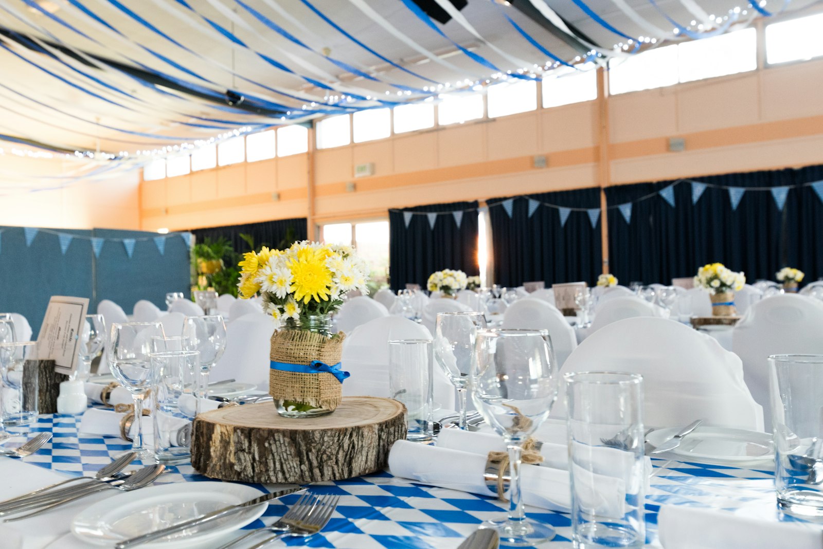 Salón de eventos con mesas vestidas y luces colgantes.